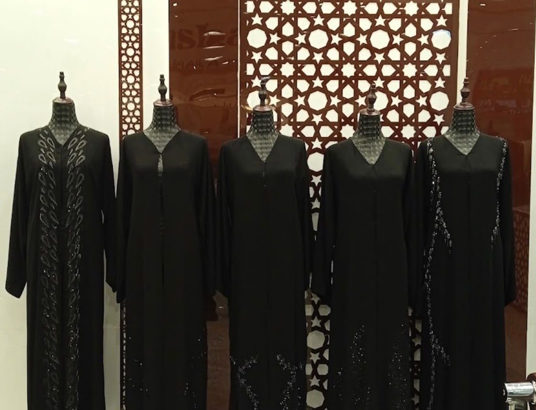 A row of embellished black abayas on mannequins