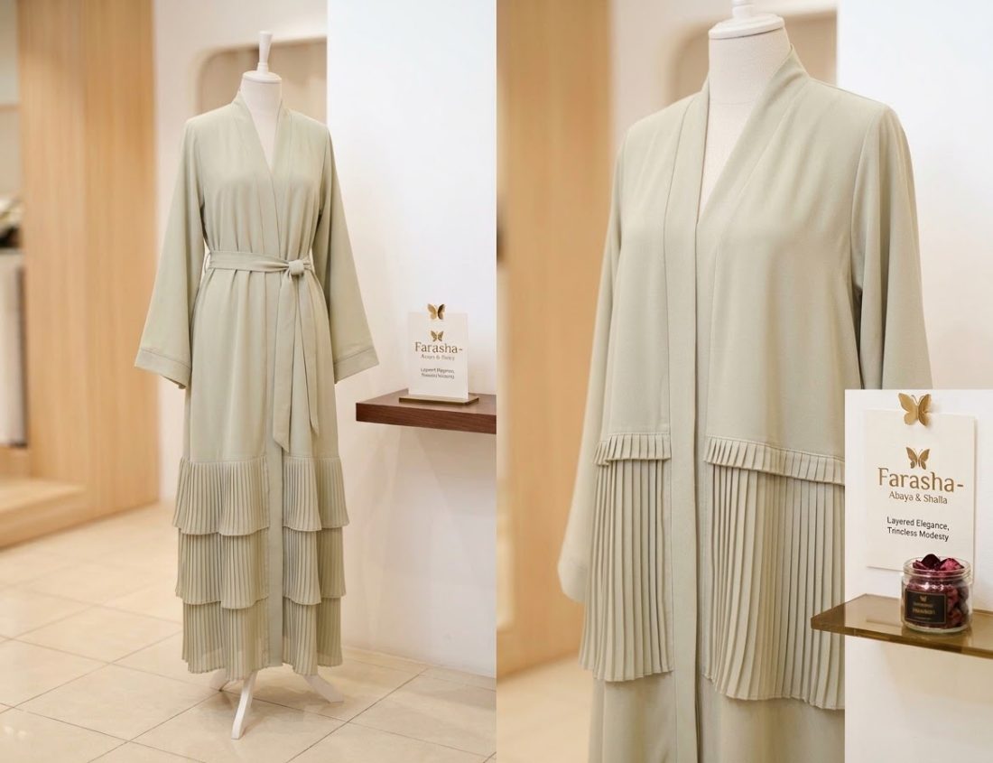 Sage belted abaya with pleated tiers, displayed in the boutique